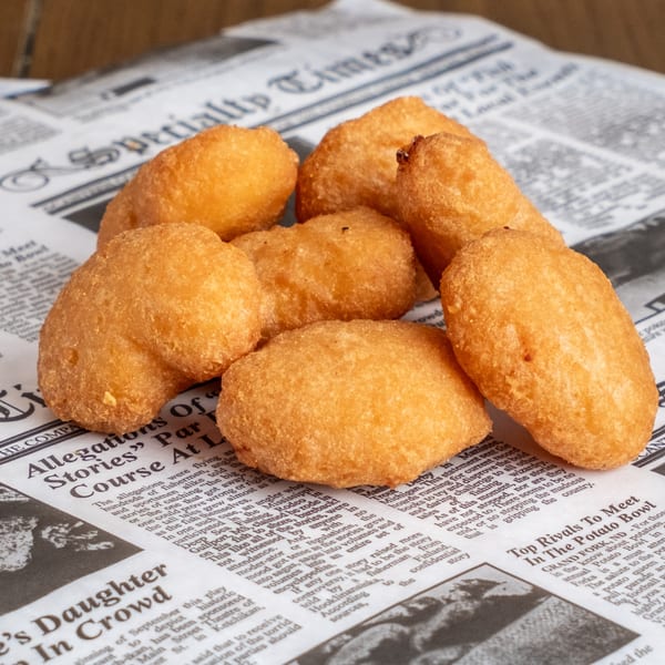Golden-brown fried pastries arranged on newspaper-style restaurant paper.