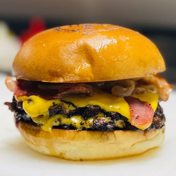 Close-up of a double cheeseburger with bacon, melted cheese, and caramelized onions on a brioche bun.